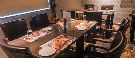 A conference room with a long table, chairs, a projector screen, and framed artwork on the wall.