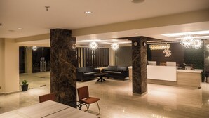 Eine moderne Hotelhalle mit Rezeption, Sitzgelegenheiten und einem Essbereich.