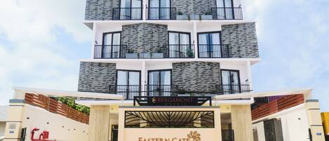 A multi-story hotel with a modern design, featuring balconies and a prominent entrance with a sign for Eastern Gate.