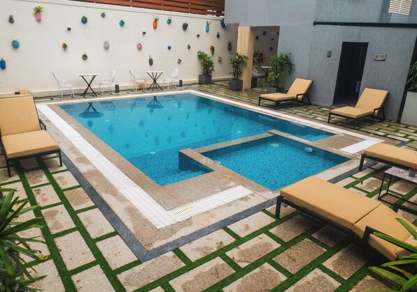 A pool area with lounge chairs, a table, and potted plants. - EASTERN GATE-A BERGAMONT GROUP OF HOTELS (Port Blair)