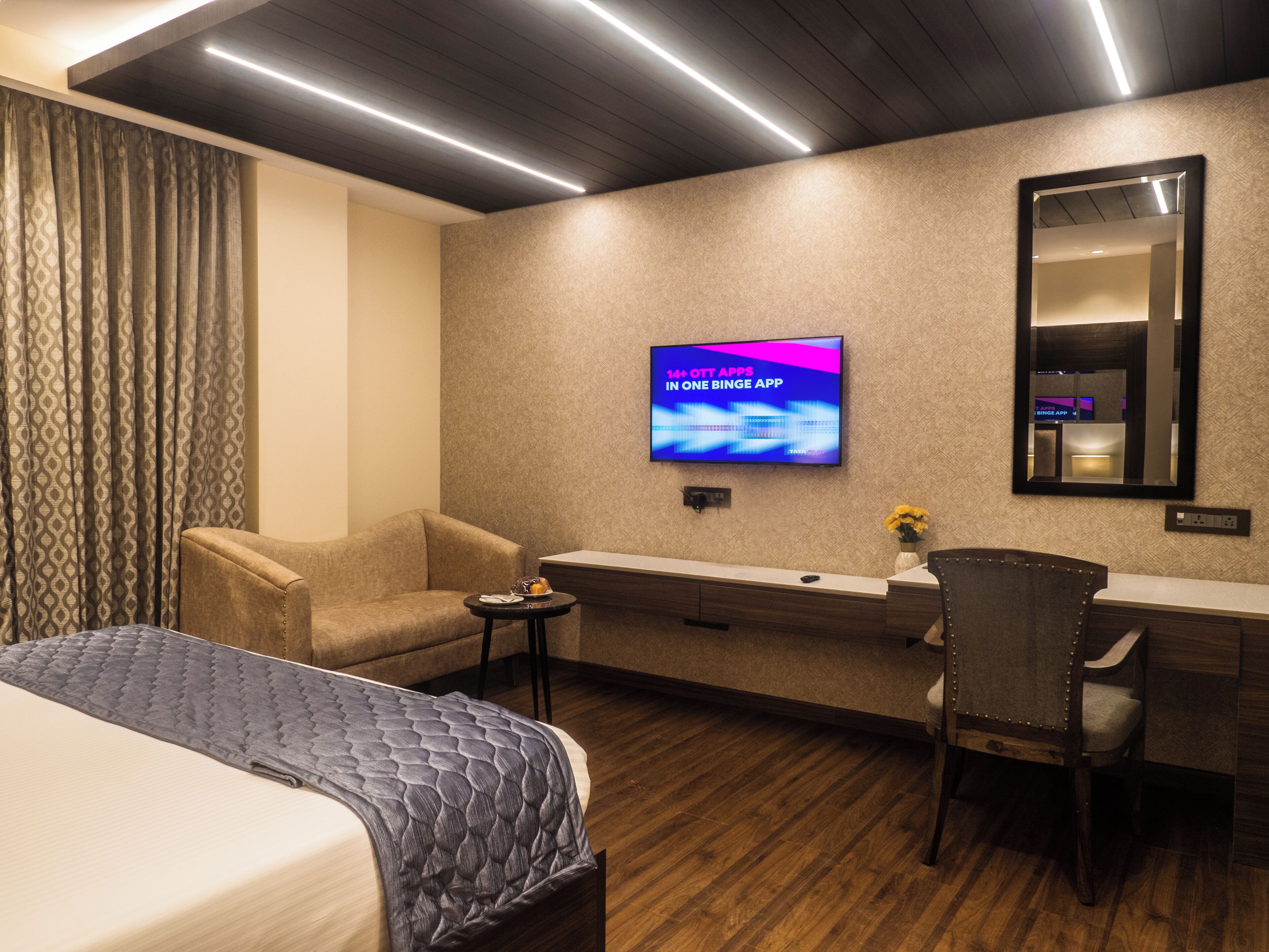 A hotel room with a bed, a desk, a chair, a television, and a mirror.
