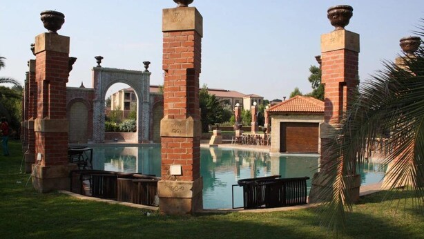 Zona de piscina con pilares de ladrillo y vista despejada de un edificio al fondo.