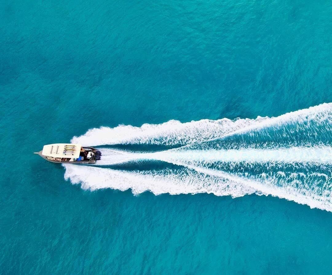 Een boot die een kielzog achterlaat in turquoise water.