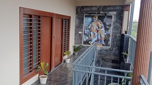 En balkon med marmorgulv, en trädør og et muralmaleri af guder.