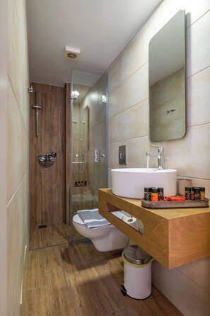 Ein modernes Badezimmer mit einer Duschkabine, einem weißen Waschbecken und einer Holzausstattung.