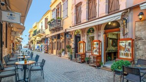 Une rue pavée bordée de cafés et de boutiques, avec des terrasses et un hôtel de charme.