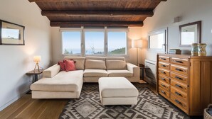Un salon avec un canapé d’angle, un meuble en bois et un tapis à motifs.