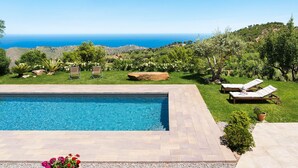 Une piscine avec des chaises longues et vue sur la mer.