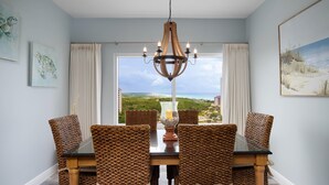 Un comedor con vistas al océano, que incluye una mesa de madera y sillas tejidas con lazos.