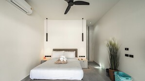 A modern hotel room with a large bed, bedside tables, a ceiling fan, an air conditioning unit, a potted plant, and a laundry basket. - Super modern Brand new Beautiful V162 (Rawai)