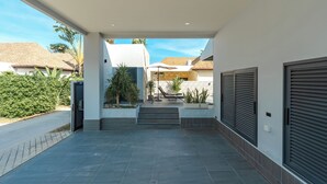 A modern building entrance with a covered patio, steps leading to a door, and a view of neighboring houses. - Super modern Brand new Beautiful V162 (Rawai)