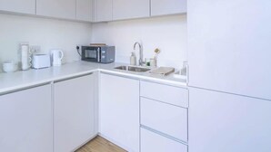 Eine moderne Küche mit weißen Schränken, einer Mikrowelle, einem Toaster und einem Spülbecken.