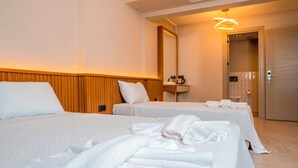 A hotel room with two beds, a wooden headboard, a bedside table with a lamp, a mirror, and a bathroom visible through an open door. - Sylvana Hotel (Ayvacik)