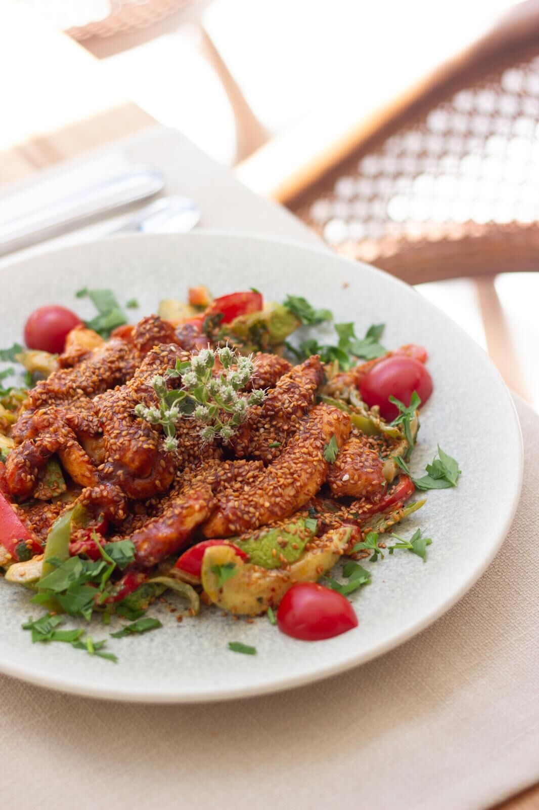 A plate of food with sesame seeds, tomatoes, and greens.
