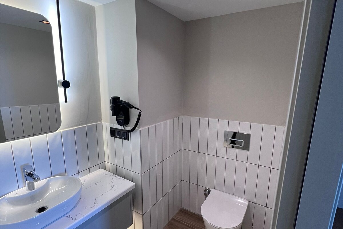 A modern bathroom with a white sink, mirror, and toilet.