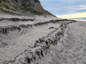 A sandy beach with wooden structures protruding from the sand. - 6 Person Holiday Home in Lokken (Lokken)