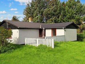 A single-story building with a white exterior, a red door, and a small porch with a white picket fence. - 6 Person Holiday Home in Lokken (Lokken)
