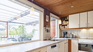 Une cuisine équipée d’un lave-vaisselle, d’une cuisinière et d’une machine à café. Une fenêtre offre une vue sur l’extérieur.