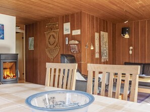 A cozy room with a wooden interior, a fireplace, two wooden chairs, a table with a glass bowl, and various wall decorations.