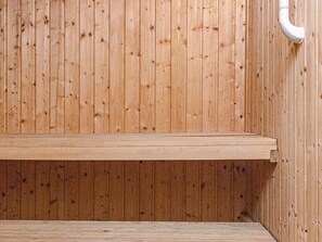 A wooden sauna with a bench and a white pipe. - 6 Person Holiday Home in Lokken (Lokken)