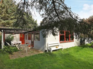 A small cabin with a red-framed window, a covered patio area, and a white exterior. - 6 Person Holiday Home in Lokken (Lokken)