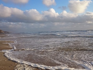 A beach with waves, a clear sky, and clouds. - 6 Person Holiday Home in Lokken (Lokken)
