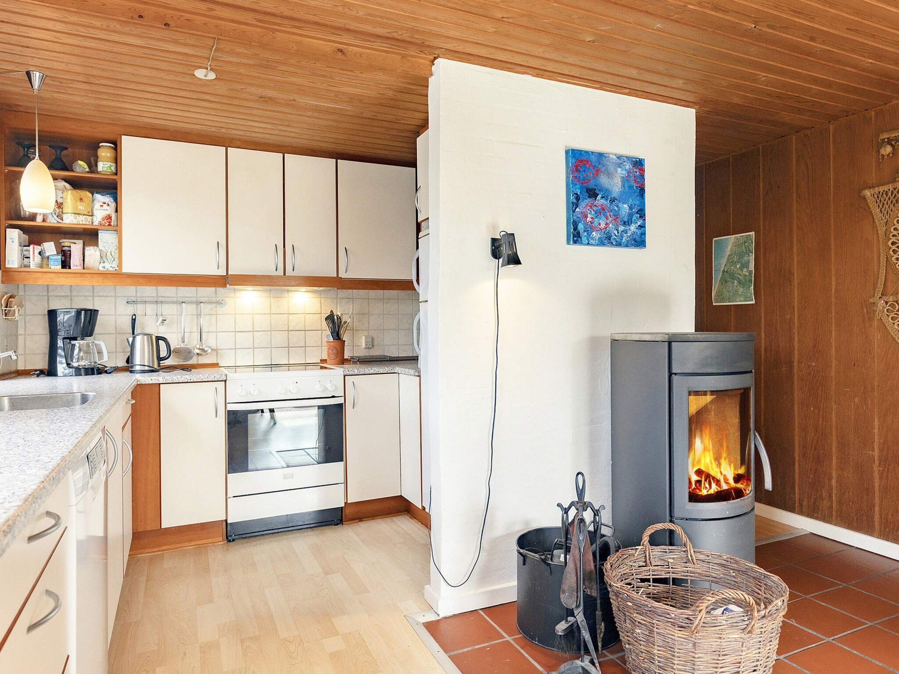 A modern kitchen with white cabinets, a stove, and a wood-burning stove.