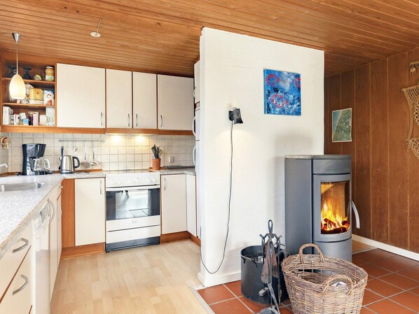 Une cuisine moderne avec des meubles blancs, une cuisinière et un poêle à bois.