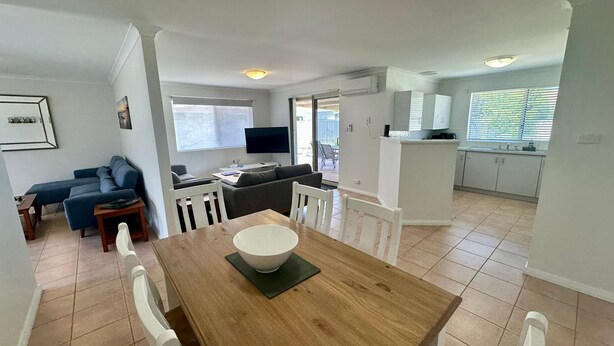 Un espace de vie moderne comprenant un coin repas, un ensemble de canapés, un téléviseur et un coin cuisine.