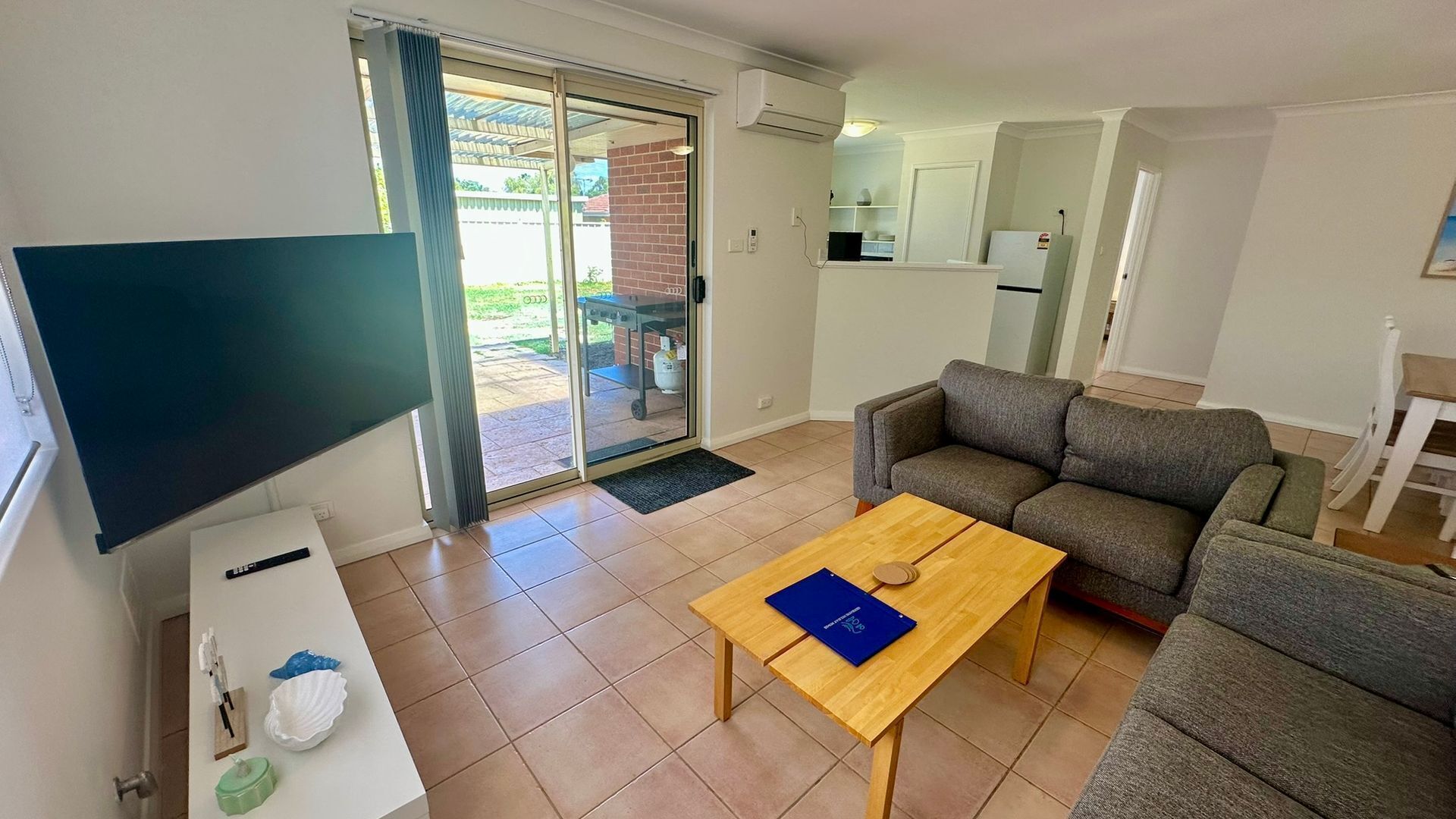Ein Wohnzimmer mit einer Couch, einem Couchtisch, einem Fernseher und einer Glastür zum Patio.