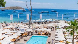 A resort with a swimming pool, beach umbrellas, and a view of the sea with boats. - Villa flamingo súper lujo (Llucmajor)