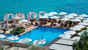 A poolside area with sun loungers and umbrellas, a pool, and a view of the sea. - Villa flamingo súper lujo (Llucmajor)