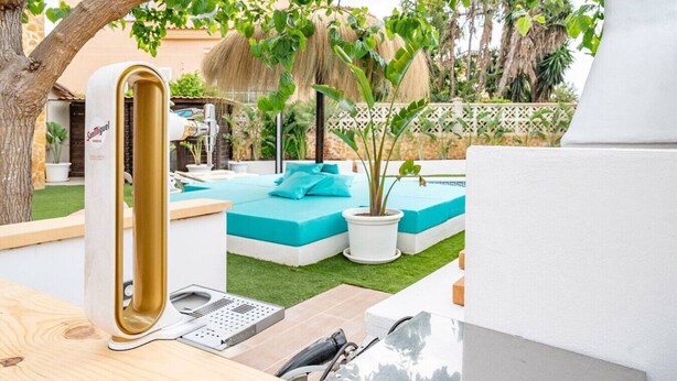 A modern outdoor pool area with a built-in sauna, a small seating area, and a well-maintained lawn.