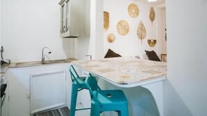 A compact kitchen with a white cabinet, a sink, and a small dining area with turquoise chairs.