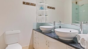 A modern bathroom with two sinks, a toilet, and a shower area. - Charming studio with WiFi, fitness room in delightful Port Douglas. (Port Douglas)