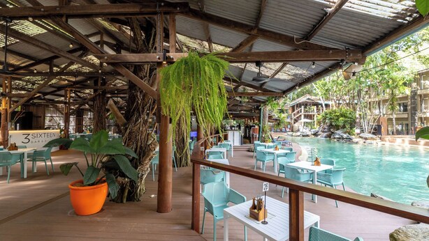 A poolside area with tables and chairs, a sign for '3 SIXTEEN BAR & BISTRO', and a large potted plant. - Charming studio with WiFi, fitness room in delightful Port Douglas. (Port Douglas)