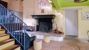 Un salon avec une cheminée, un escalier et une porte.