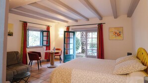 Une chambre à coucher avec un lit, une chaise, une table et une fenêtre avec des rideaux.