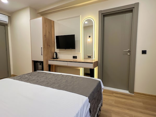 Une chambre à coucher avec un lit, une télévision, un bureau et une porte.
