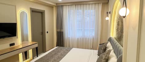 Un dormitorio moderno con cama, televisor y escritorio.