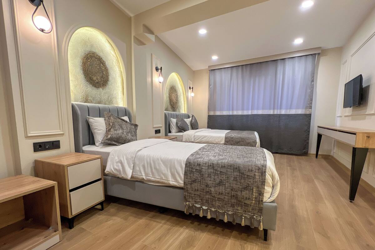 A modern bedroom with a large bed, bedside tables, a desk, and a TV.