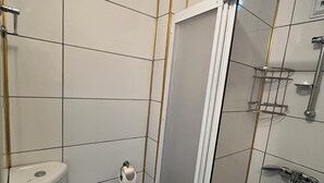 Un baño pequeño con inodoro, cabina de ducha y lavamanos.