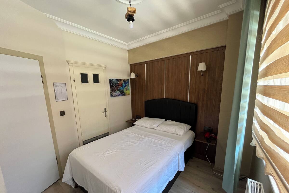 A bedroom with a bed, a wardrobe, a bedside table, and a lamp.