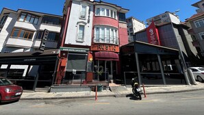 Un edificio en esquina con una cafetería y un bistró en la planta baja, un toldo rojo y un letrero que dice Rustic.