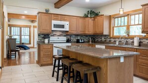 Una cocina moderna con armarios de madera, una isla central con taburetes, un microondas y un fregadero.