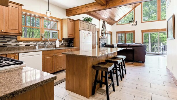 Una cocina amplia con armarios de madera, encimera de granito y una isla grande con taburetes de bar.