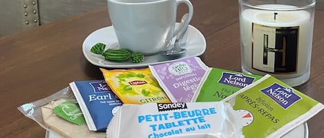 A hotel room with a bed, a bedside table with a cup, a candle, and various breakfast items.