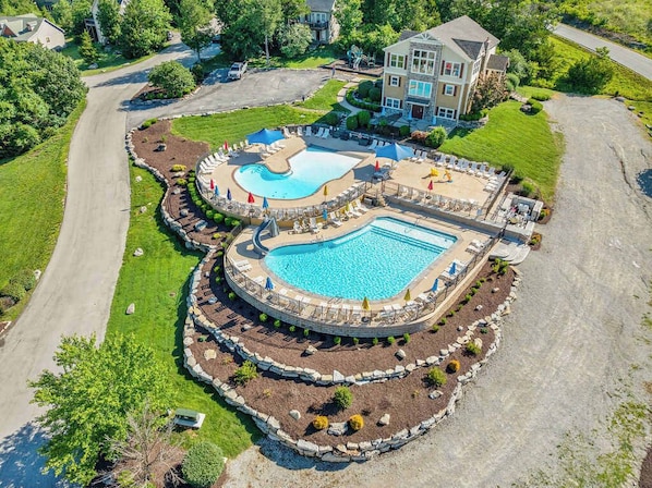 Une grande piscine extérieure dotée d’une terrasse circulaire, entourée de chaises longues et de parasols.
