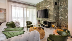 Een moderne woonkamer met een grote flatscreen televisie, een open haard en een comfortabele zithoek.