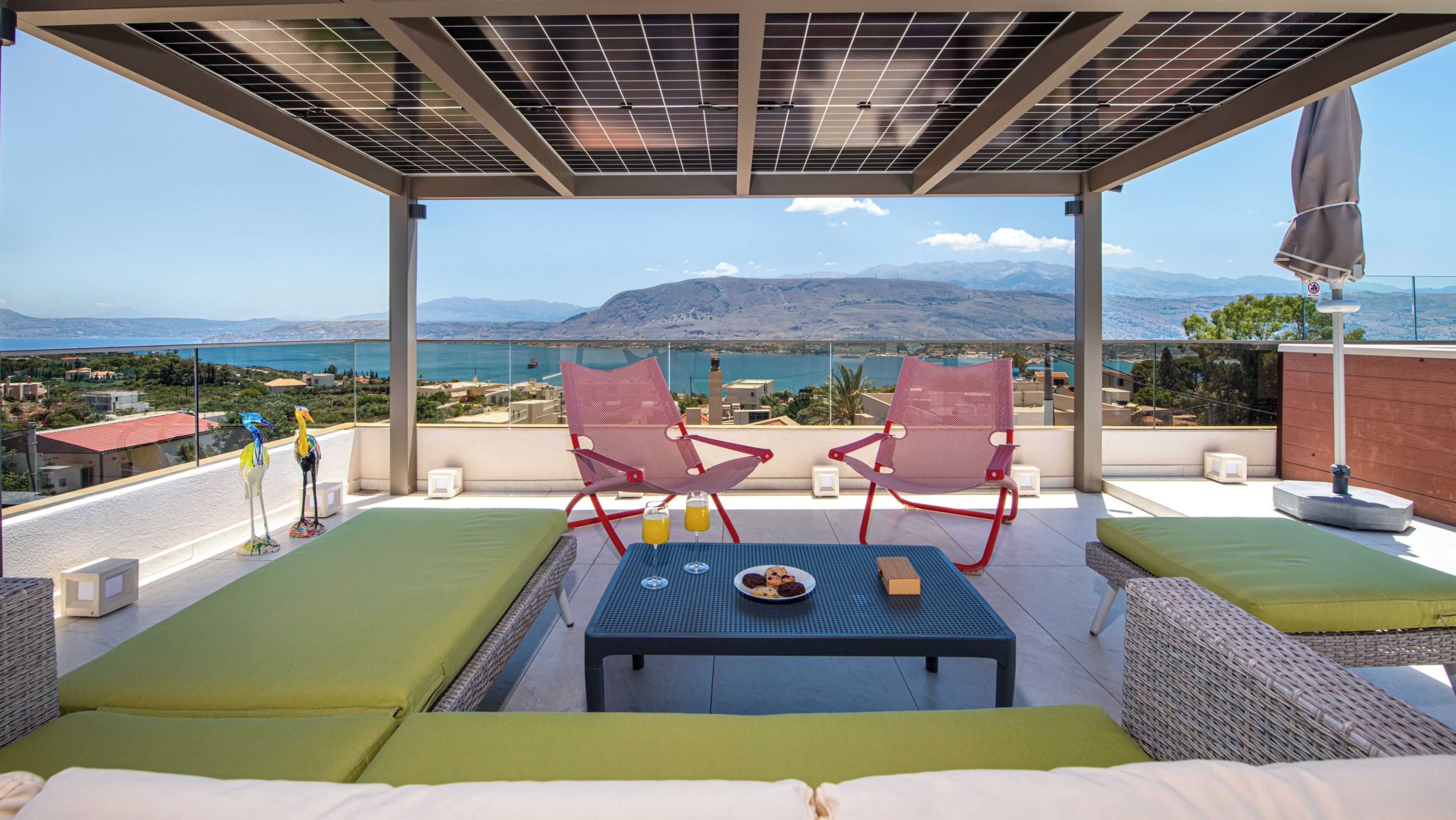 Une terrasse avec deux chaises, une table et une vue sur la mer et les montagnes.